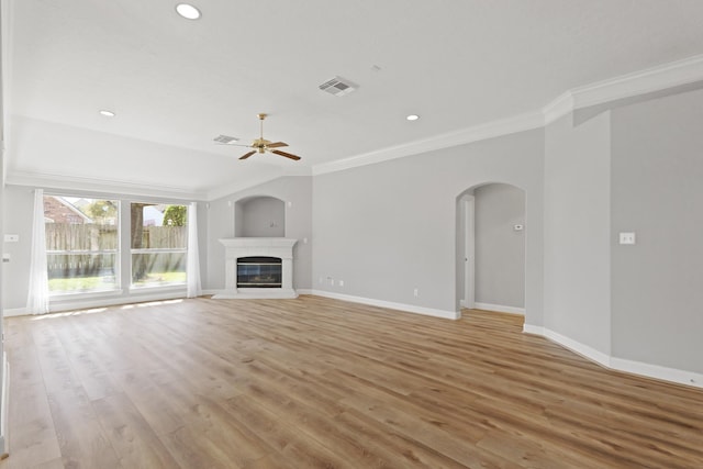 unfurnished living room featuring ornamental molding, a glass covered fireplace, arched walkways, light wood finished floors, and baseboards