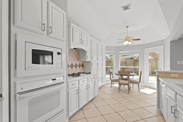 kitchen featuring visible vents, backsplash, white appliances, and light countertops