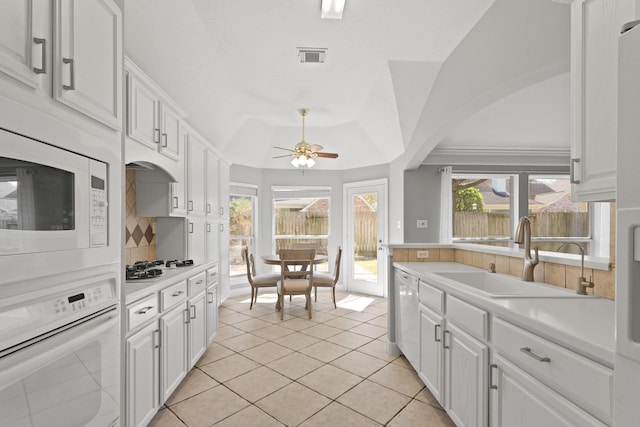 kitchen with a healthy amount of sunlight, light countertops, white cabinets, white appliances, and a sink