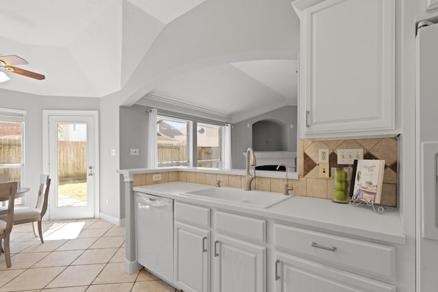 kitchen featuring vaulted ceiling, light tile patterned floors, decorative backsplash, white dishwasher, and a sink