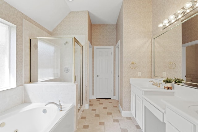 full bathroom with a stall shower, a jetted tub, wallpapered walls, double vanity, and vaulted ceiling