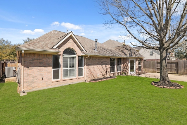 back of house featuring fence, a yard, a shingled roof, a patio area, and brick siding