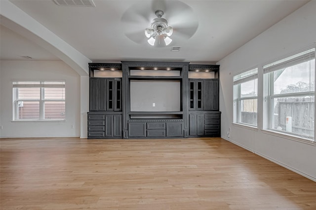 unfurnished living room with visible vents, arched walkways, ceiling fan, and light wood finished floors