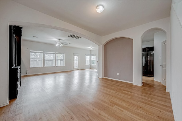 spare room featuring light wood-type flooring, visible vents, and arched walkways