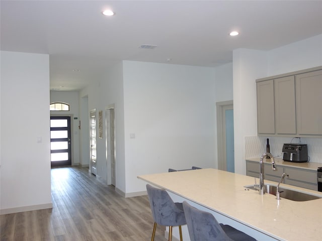 kitchen featuring visible vents, recessed lighting, a sink, gray cabinetry, and light wood-type flooring