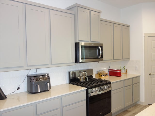 kitchen featuring light countertops, gray cabinetry, tasteful backsplash, and stainless steel appliances