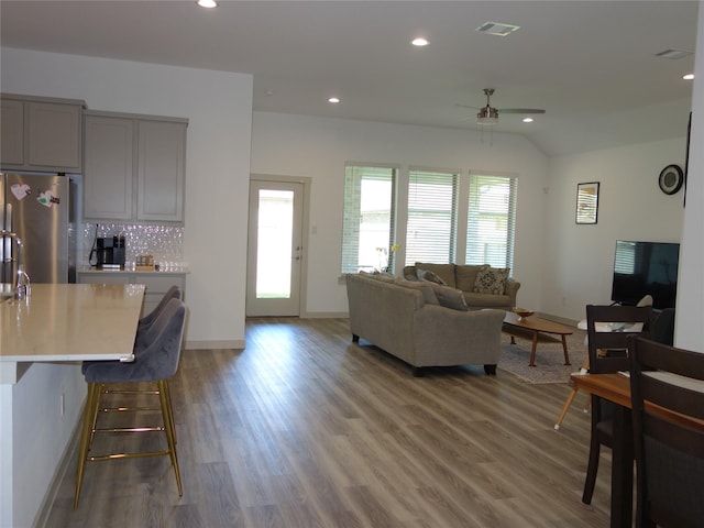 living room featuring recessed lighting, wood finished floors, and vaulted ceiling