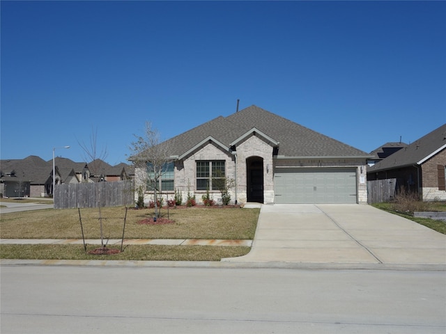 french country inspired facade with a shingled roof, a front lawn, fence, driveway, and an attached garage