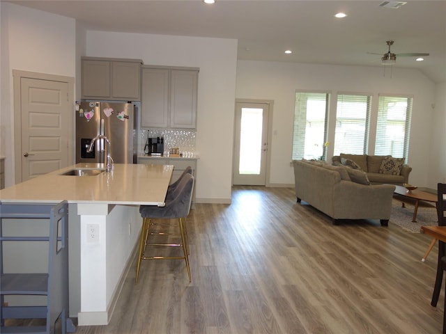 kitchen with tasteful backsplash, stainless steel fridge with ice dispenser, light countertops, gray cabinets, and a sink