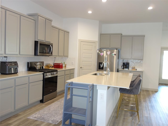 kitchen featuring appliances with stainless steel finishes, light wood-style floors, gray cabinetry, and a sink