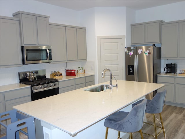 kitchen featuring tasteful backsplash, gray cabinets, stainless steel appliances, and a sink