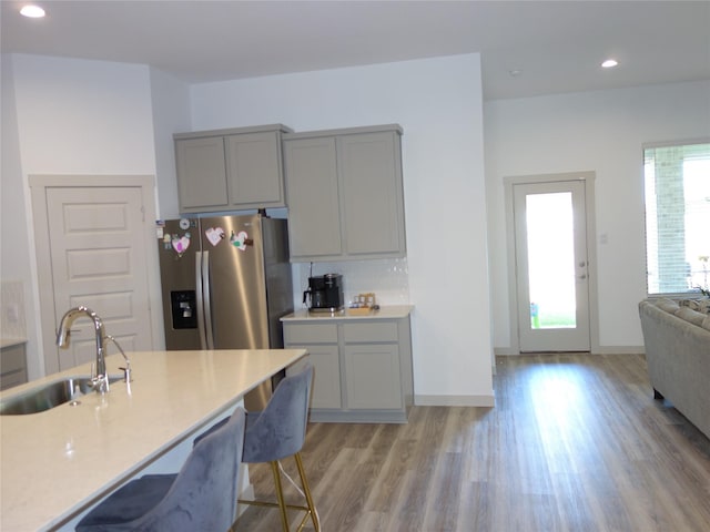 kitchen featuring light wood-type flooring, gray cabinetry, stainless steel refrigerator with ice dispenser, a sink, and recessed lighting