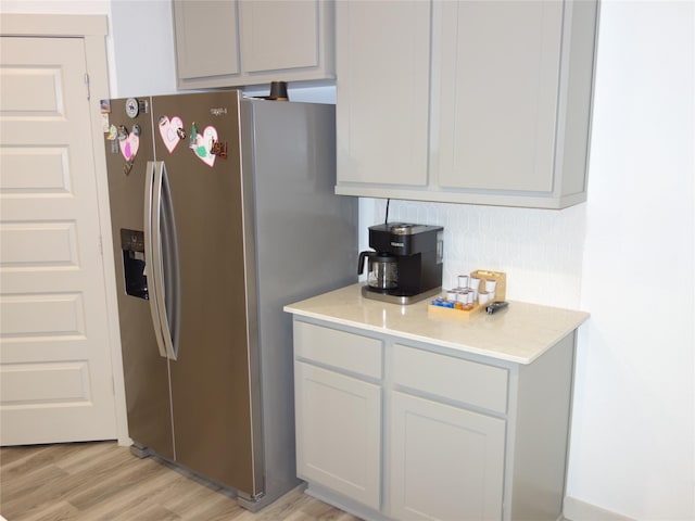 kitchen with light countertops, stainless steel refrigerator with ice dispenser, and light wood finished floors