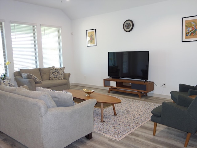 living area featuring vaulted ceiling, wood finished floors, and baseboards