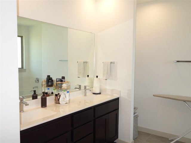 bathroom with a sink, baseboards, double vanity, and tile patterned flooring