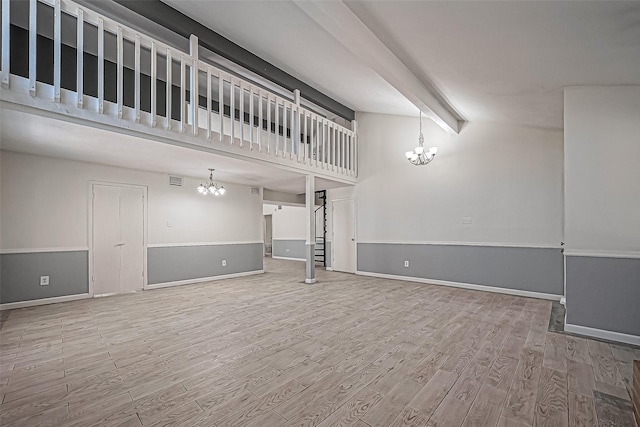 unfurnished living room featuring a notable chandelier, wood finished floors, stairway, a high ceiling, and baseboards