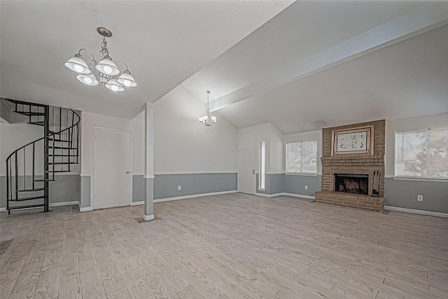 unfurnished living room with stairway, wood finished floors, vaulted ceiling with beams, a brick fireplace, and a notable chandelier