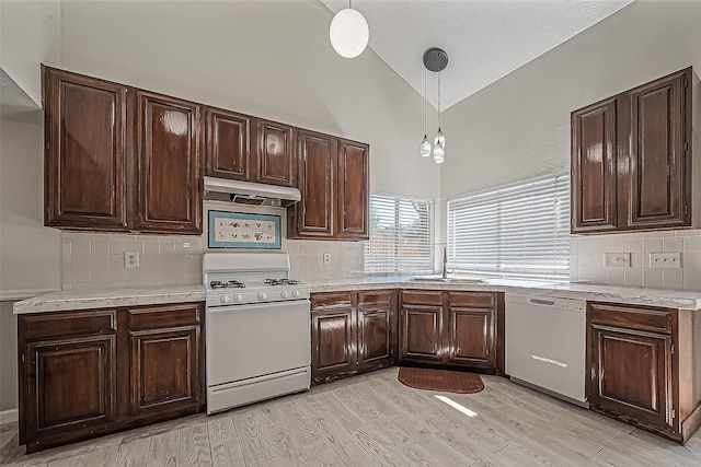 kitchen featuring under cabinet range hood, white appliances, light countertops, and a sink