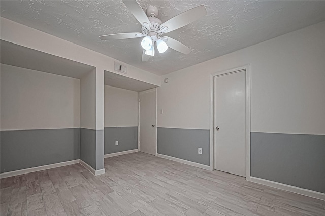 spare room featuring visible vents, a textured ceiling, ceiling fan, and wood finished floors