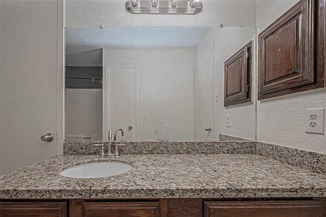 bathroom featuring vanity and a textured wall