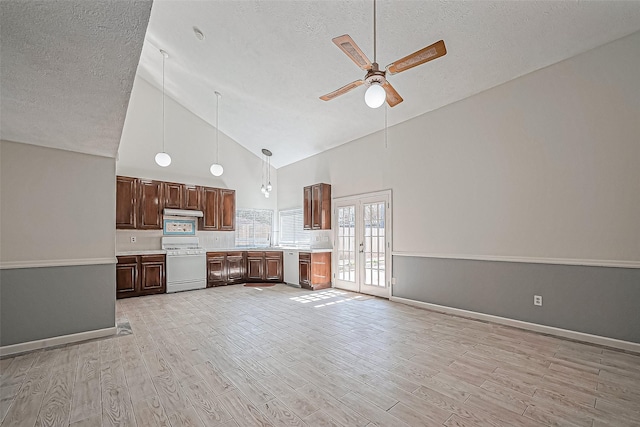 kitchen featuring light wood-style flooring, white range with gas stovetop, light countertops, french doors, and under cabinet range hood