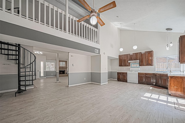 kitchen featuring light wood finished floors, a fireplace with raised hearth, light countertops, white range with gas stovetop, and a sink