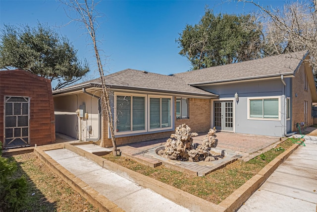 back of house featuring brick siding, a patio area, french doors, and a shingled roof