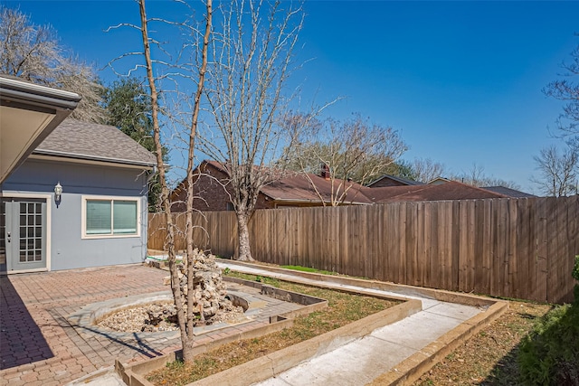 view of yard featuring a patio area, french doors, a fenced backyard, and a garden