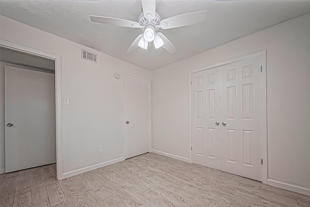 unfurnished bedroom featuring visible vents, ceiling fan, light wood-style floors, a closet, and a textured ceiling