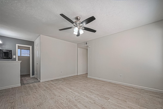 unfurnished room with light wood finished floors, visible vents, baseboards, ceiling fan, and a textured ceiling