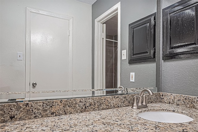 bathroom featuring vanity and a textured wall