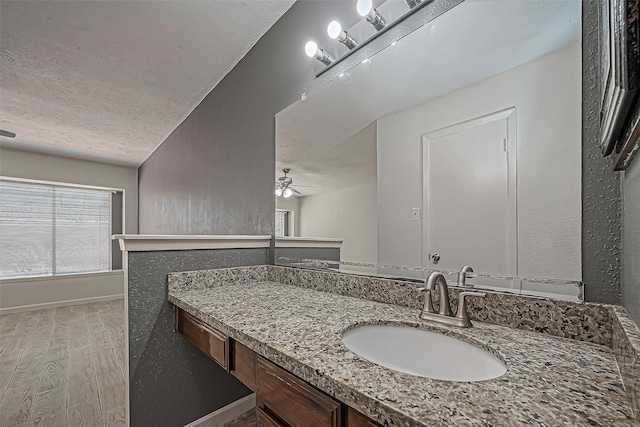 bathroom featuring wood finished floors, vanity, a textured wall, a textured ceiling, and a ceiling fan