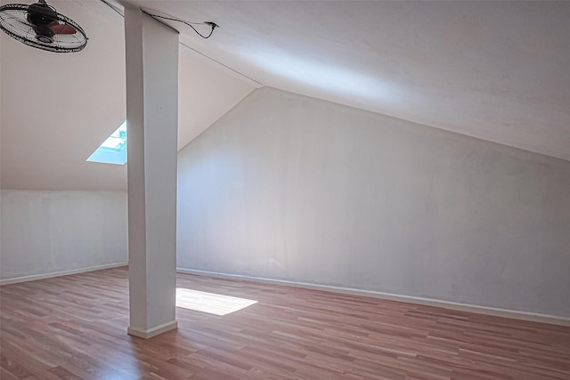 additional living space featuring lofted ceiling with skylight, wood finished floors, and baseboards