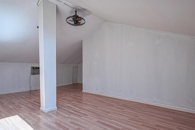 additional living space featuring vaulted ceiling, a wall mounted air conditioner, baseboards, and wood finished floors