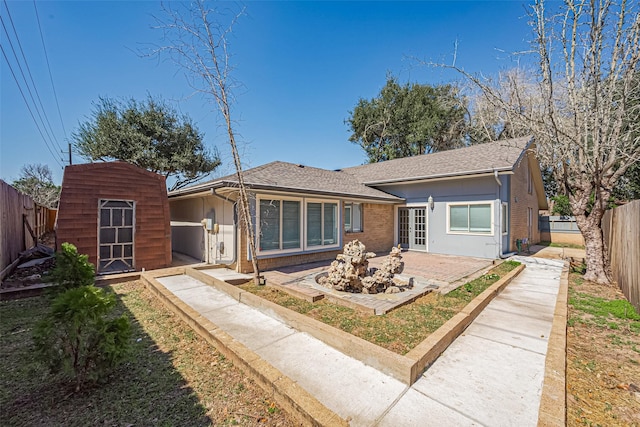 back of property with brick siding, a storage shed, an outdoor structure, a fenced backyard, and a patio