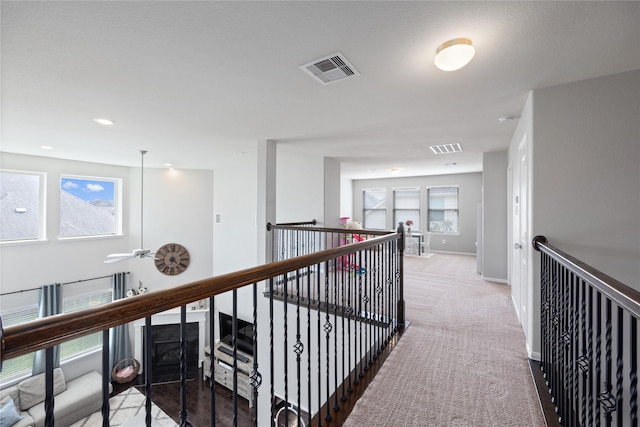 hallway featuring visible vents, carpet floors, and baseboards