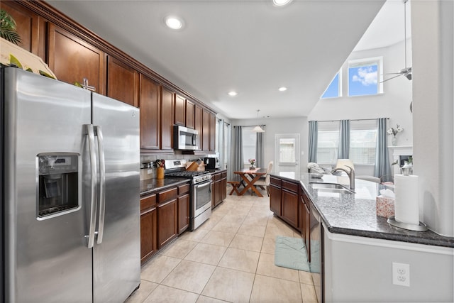 kitchen with a sink, recessed lighting, stainless steel appliances, dark stone counters, and light tile patterned floors