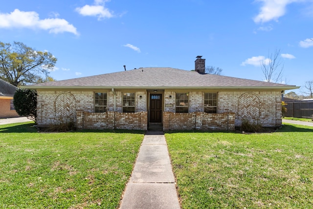 view of front facade featuring brick siding, a chimney, a front lawn, and roof with shingles