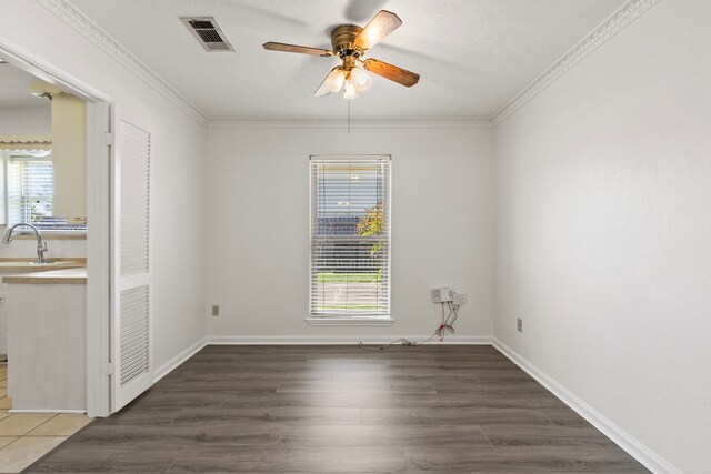 unfurnished room with a sink, visible vents, plenty of natural light, and wood finished floors