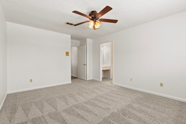 unfurnished bedroom with baseboards, visible vents, ensuite bath, a textured ceiling, and light carpet