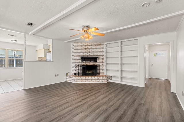 unfurnished living room with visible vents, a fireplace, a textured ceiling, and wood finished floors