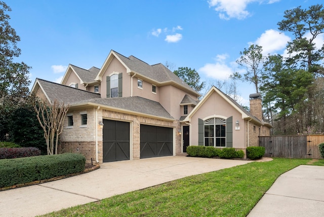 traditional-style house featuring brick siding, fence, concrete driveway, roof with shingles, and stucco siding