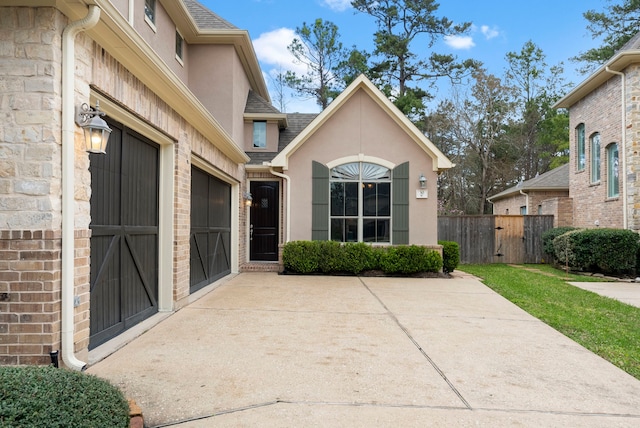 view of patio / terrace featuring an attached garage, concrete driveway, and fence