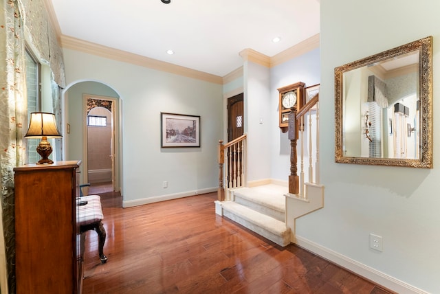 foyer entrance with crown molding, baseboards, stairway, arched walkways, and wood-type flooring