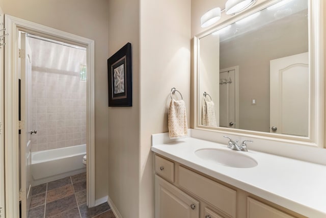 bathroom with baseboards, toilet,  shower combination, and vanity