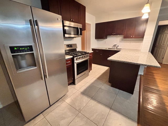 kitchen featuring backsplash, light stone countertops, appliances with stainless steel finishes, a peninsula, and a sink