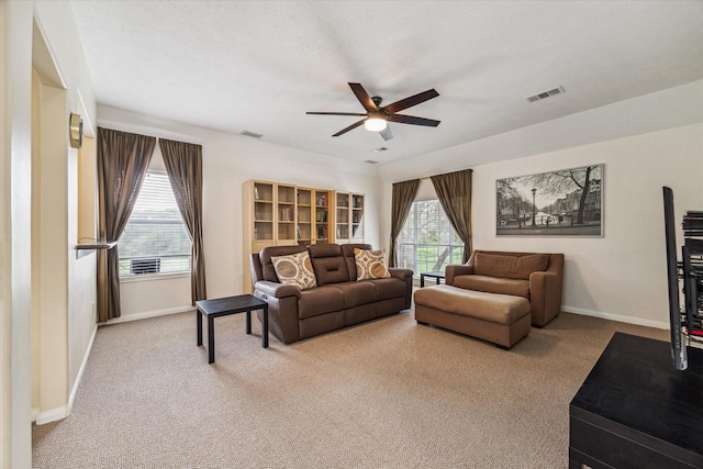 living room with baseboards, visible vents, and ceiling fan