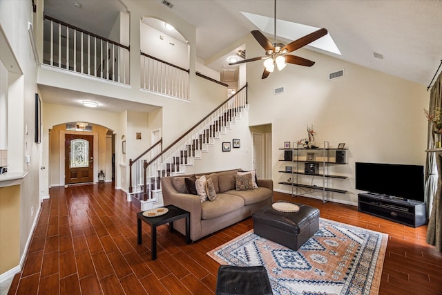 living area with wood finish floors, visible vents, stairway, arched walkways, and baseboards