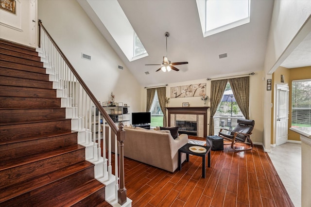 living area with visible vents, dark wood finished floors, stairway, a skylight, and a tile fireplace