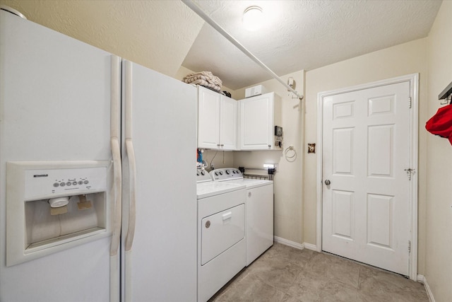 washroom with a textured ceiling, cabinet space, baseboards, and washing machine and clothes dryer